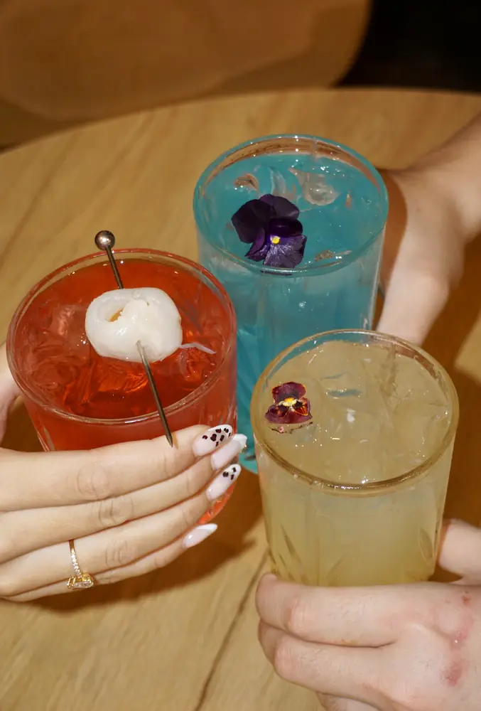Trois cocktails colorés au litchi et aux fleurs comestibles